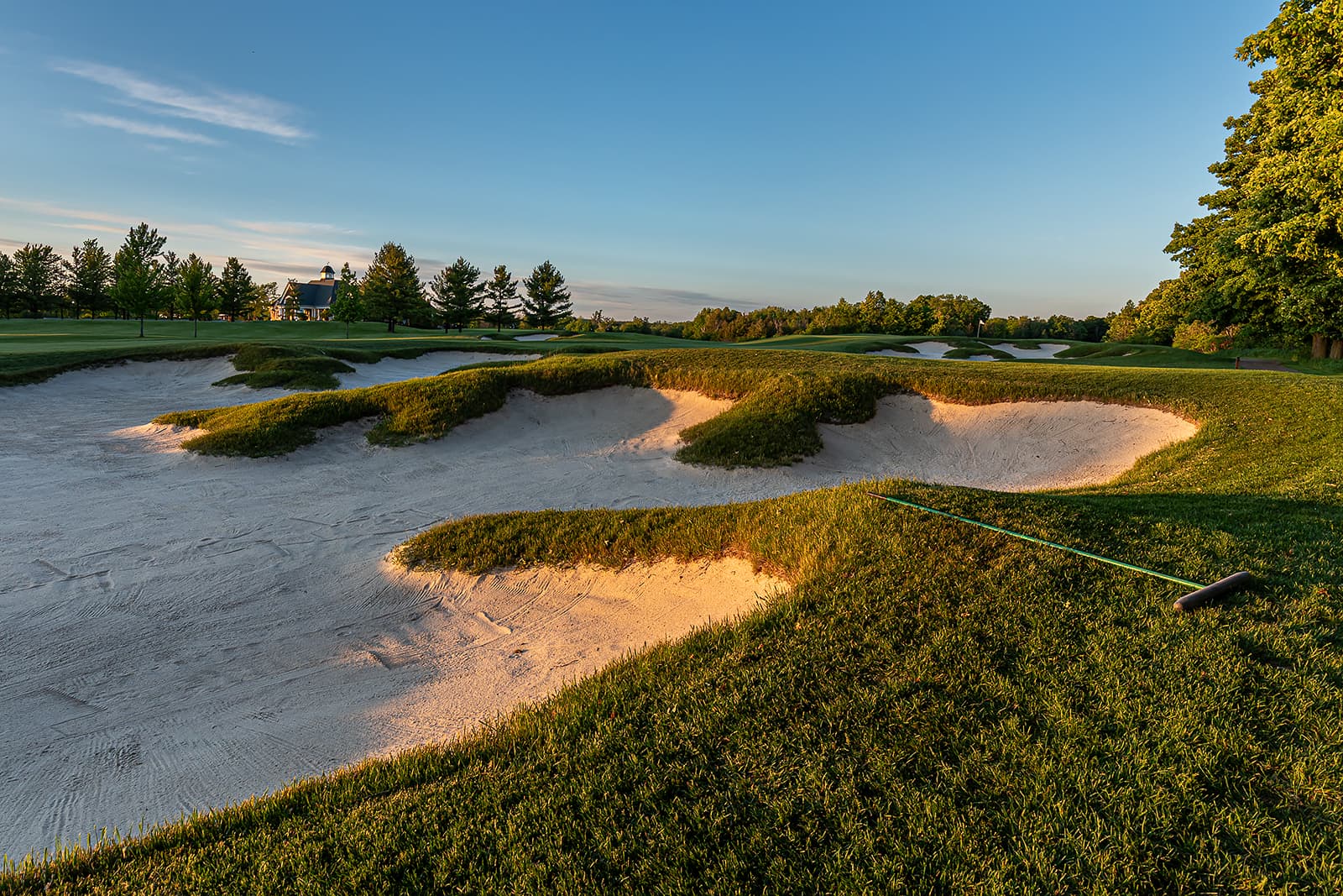 sand bunkers on Southern Ontario golf course at sunset with clubhouse in background