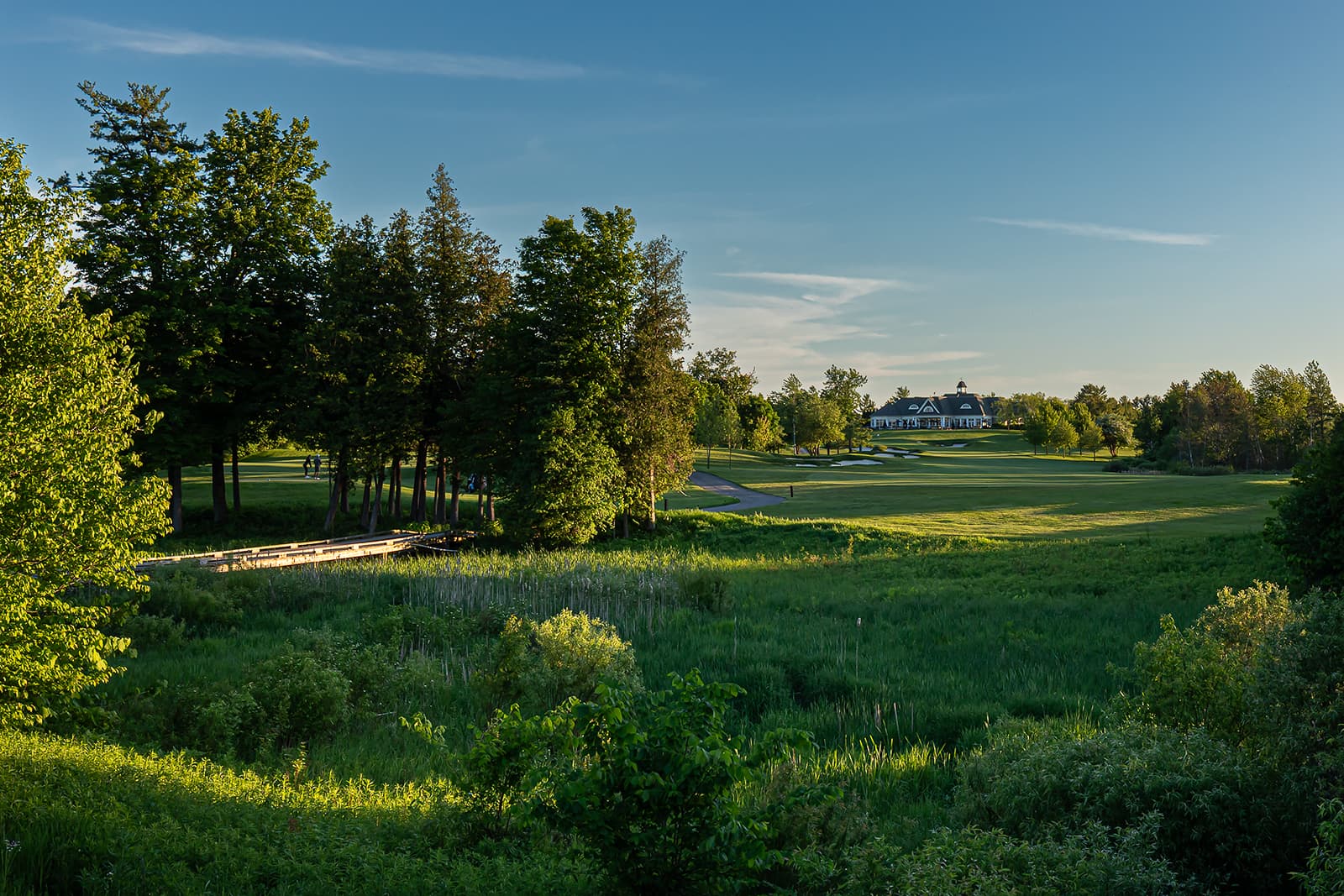 golf course clubhouse view with bridge and fairway at sunset