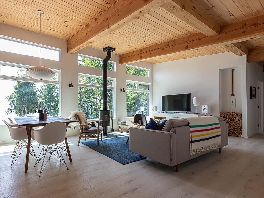 modern cabin with wood stove and large glass walls with view of the lake