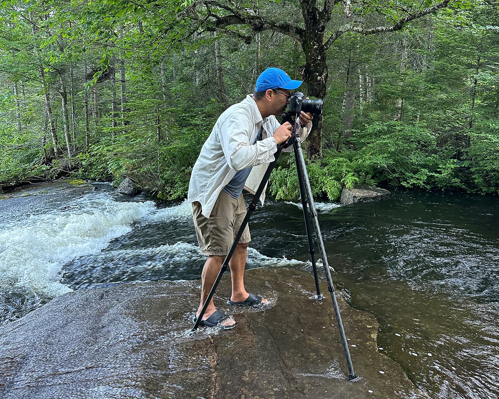 Jay standing in a river taking a photo with a tripod