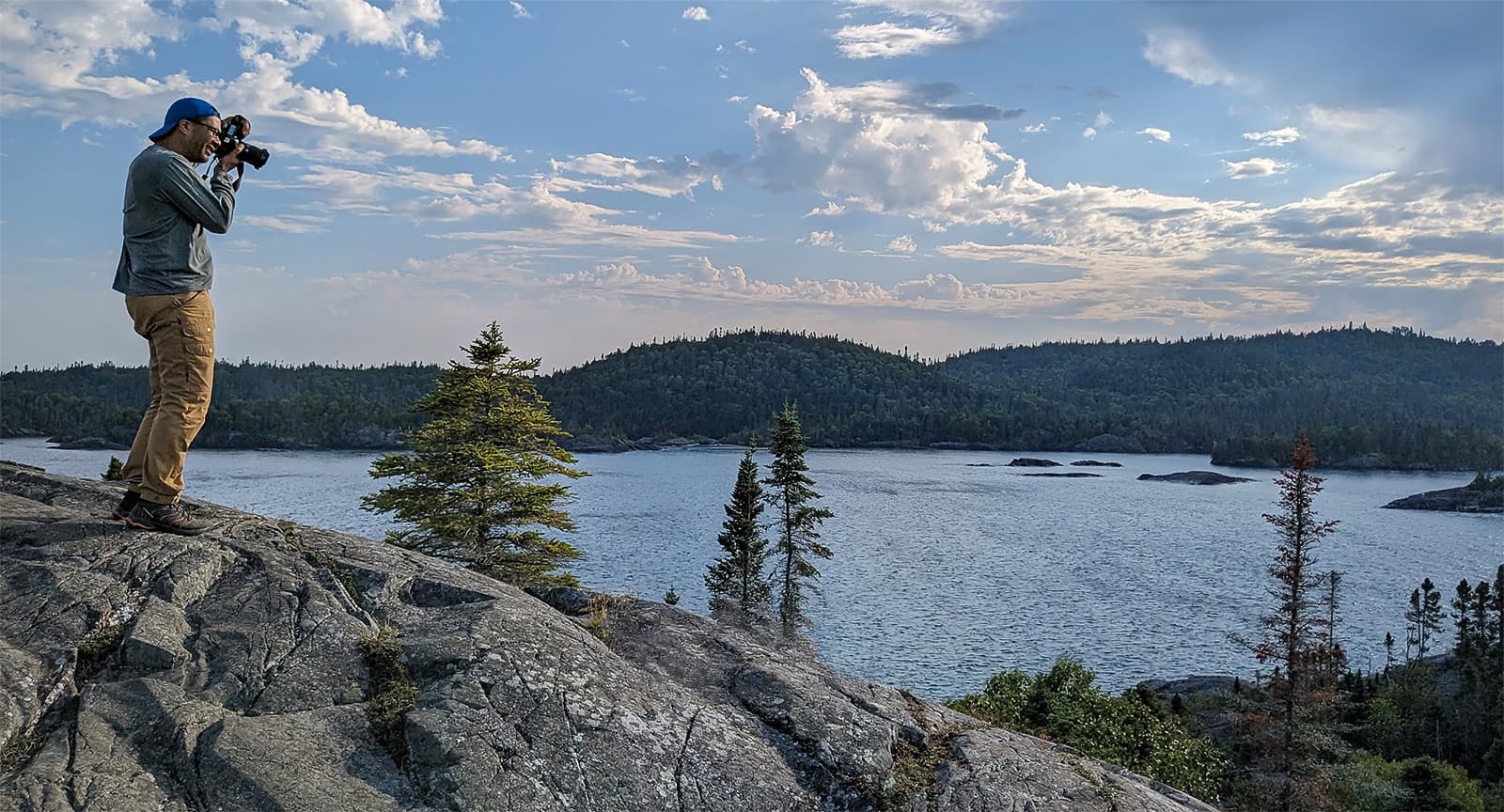 Jay Kerr standing on rock holding camera taking photo of Hatie Cove