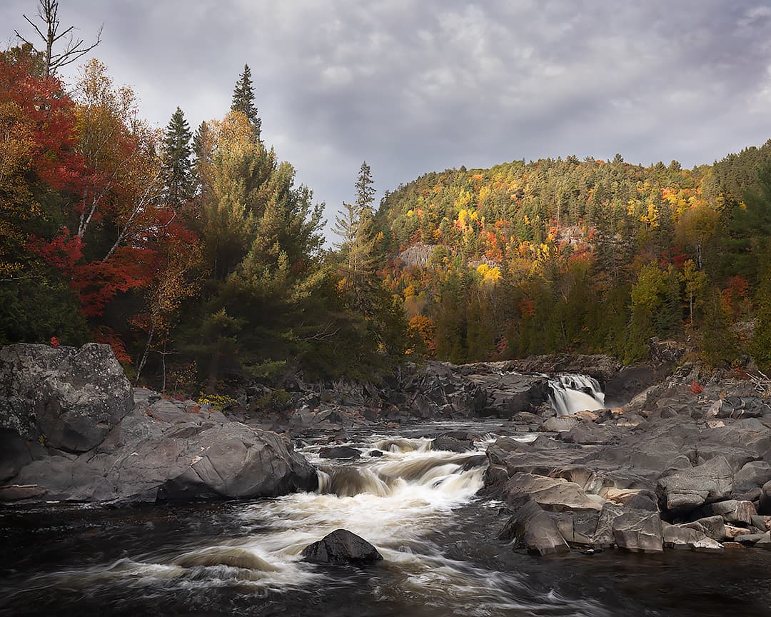 long exposure photo of waterfalls and autum color with dramatic light